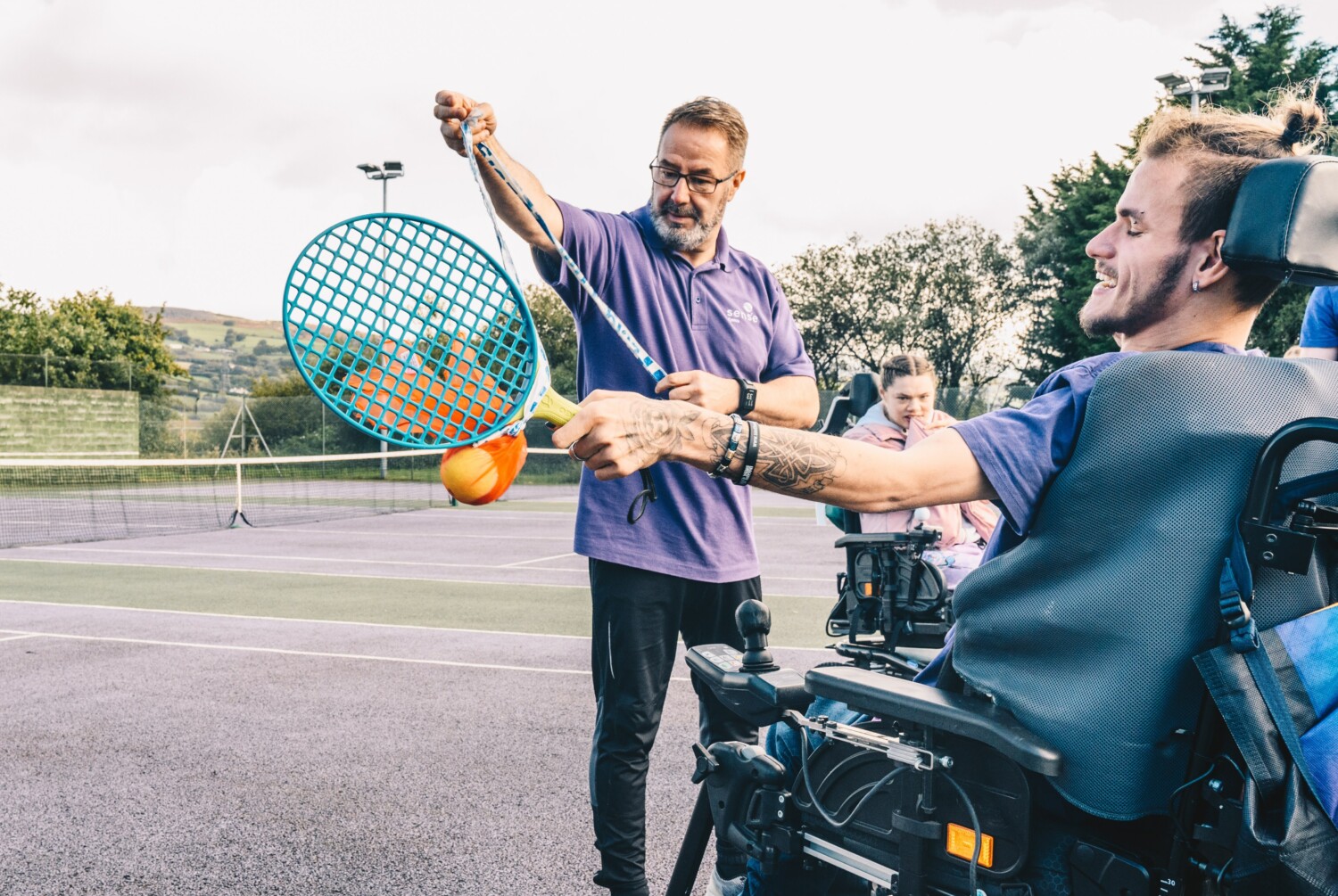 A care worker playing tennis with a care user in a wheelchair