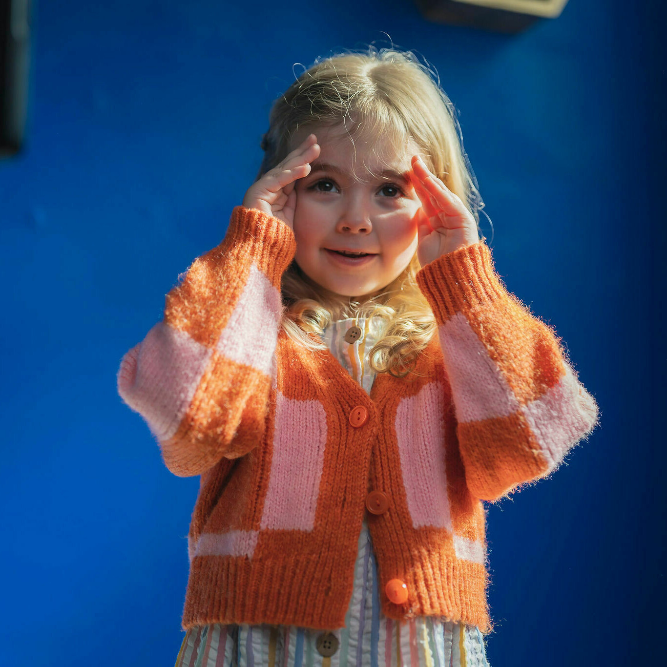 Childcare TV advert - young child with blonde hair playing peak-a-boo.