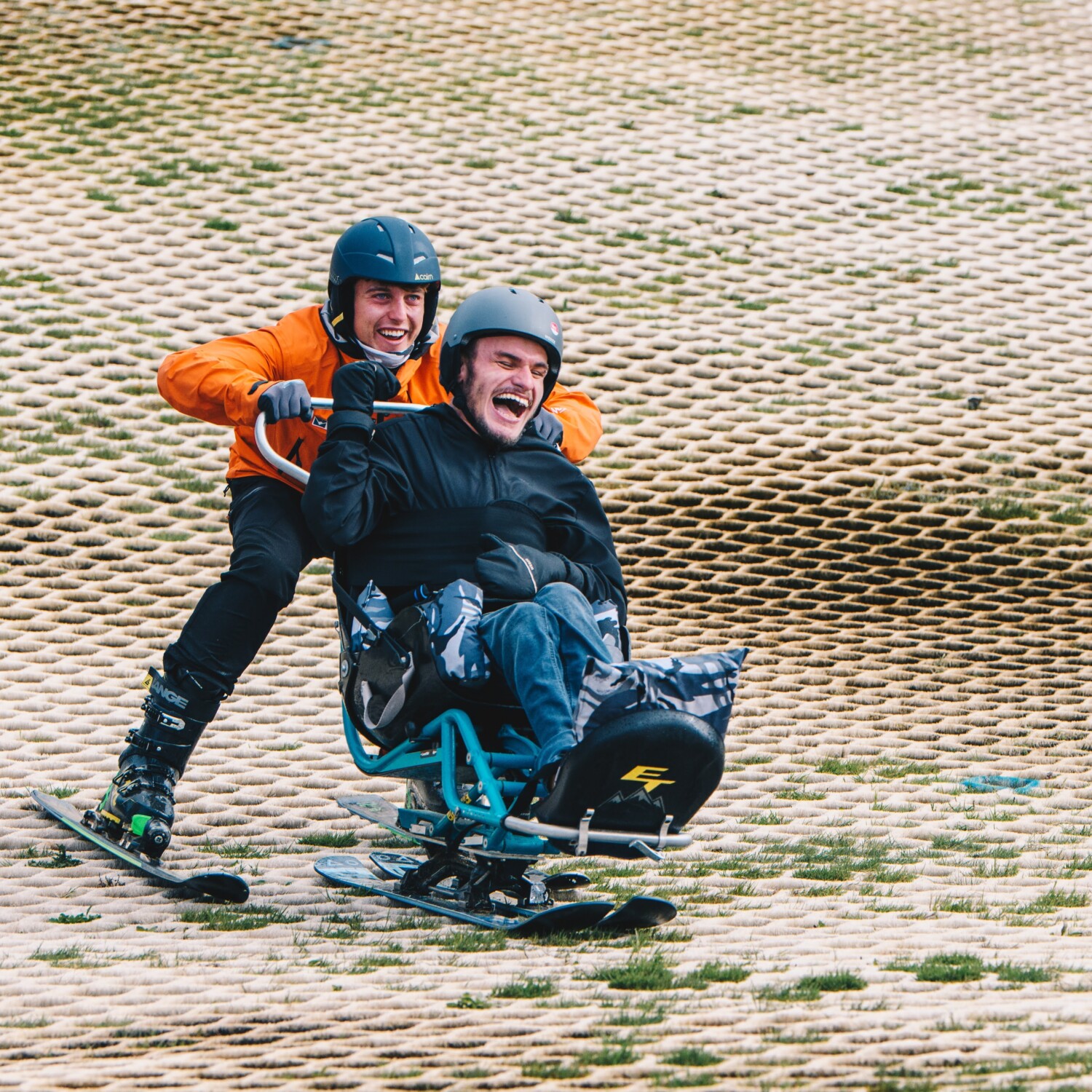 Volunteer and user of care and support skiing down a dry slope.