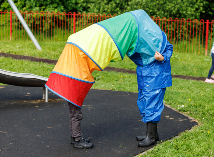 Two children playing in a colourful play tunnel with only their feet visible