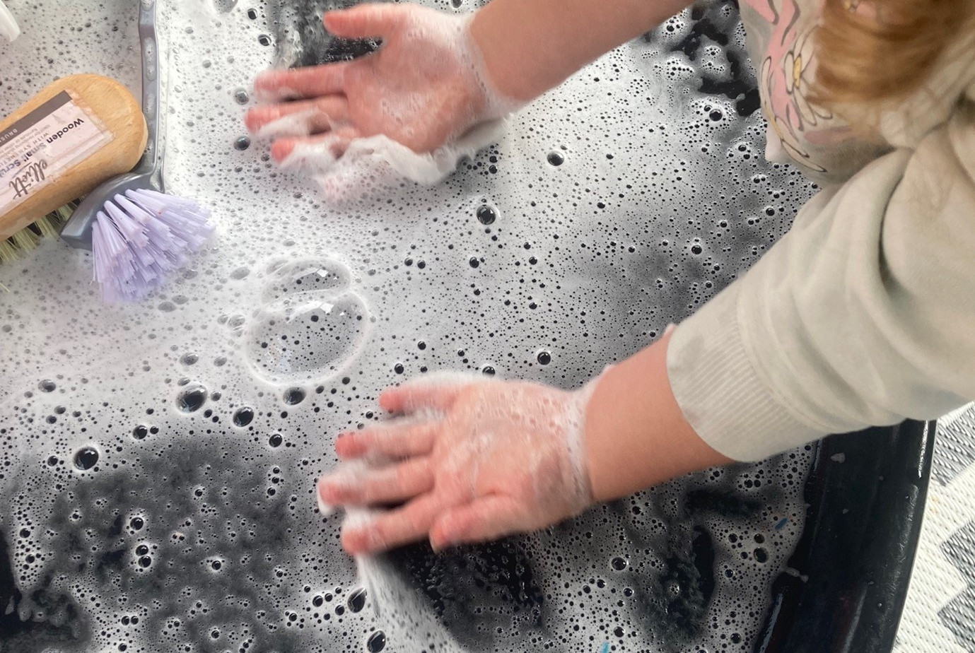 child's hands playing in bubbles