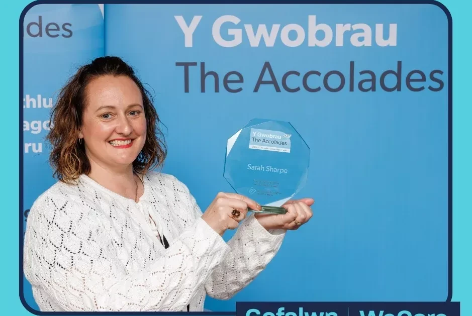 Sarah holding their award.