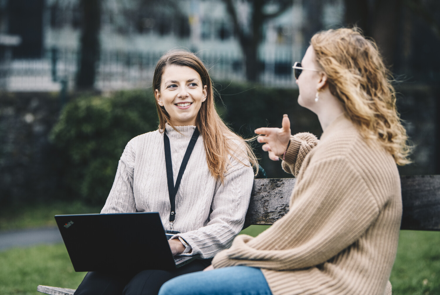 Ruby sat on a bench outside with her laptop smiling in conversation with her care user