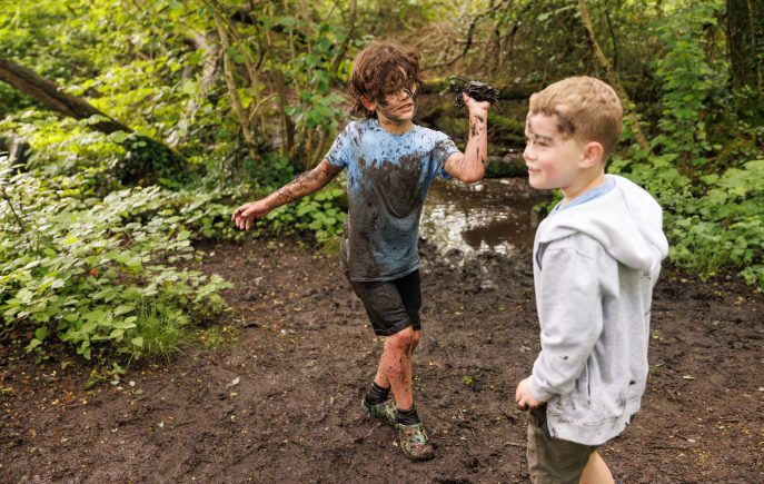 Two young boys playing in the mud