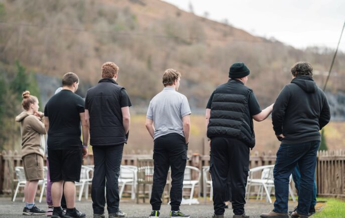 6 young people with their backs to the camera looking out at a view in country